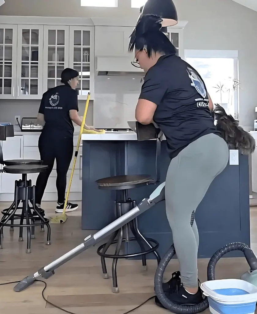 Female cleaner vacuuming the residential cleaning and kitchen floor in a high-rise apartment with modern interior
