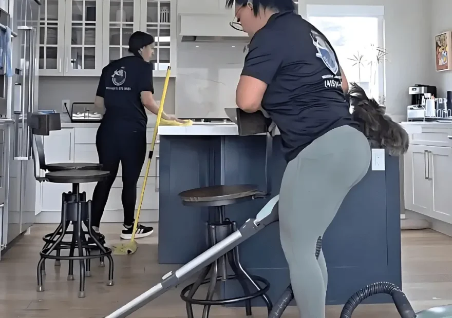 Female cleaner vacuuming the residential cleaning and kitchen floor in a high-rise apartment with modern interior